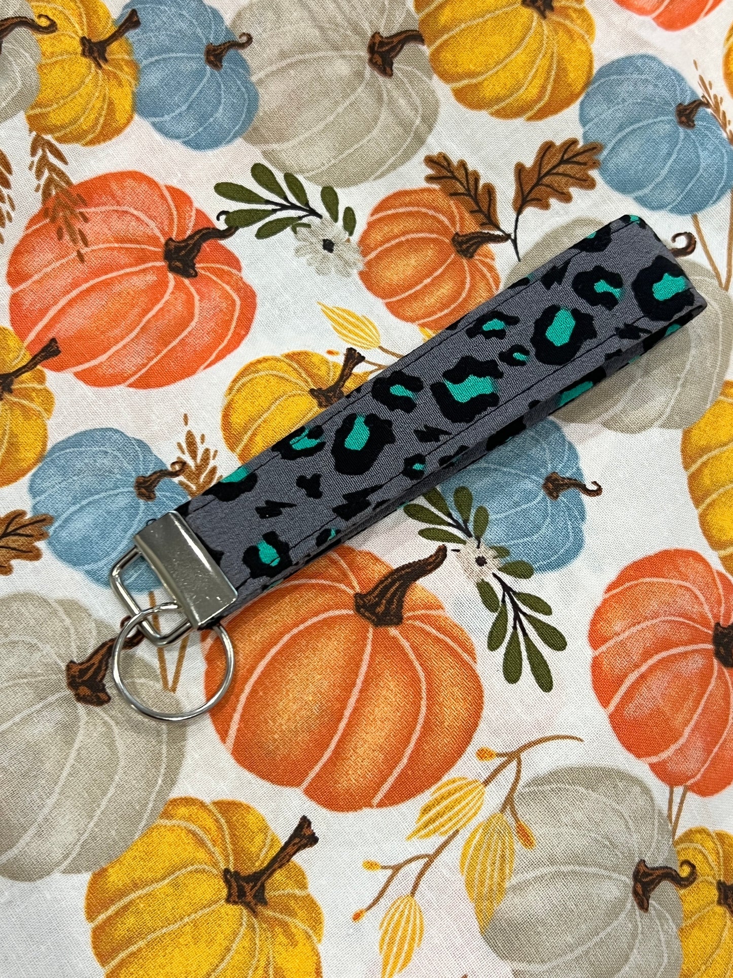 Sew Much Love grey wristlet keychain with black and teal snow leopard print, silver hardware.