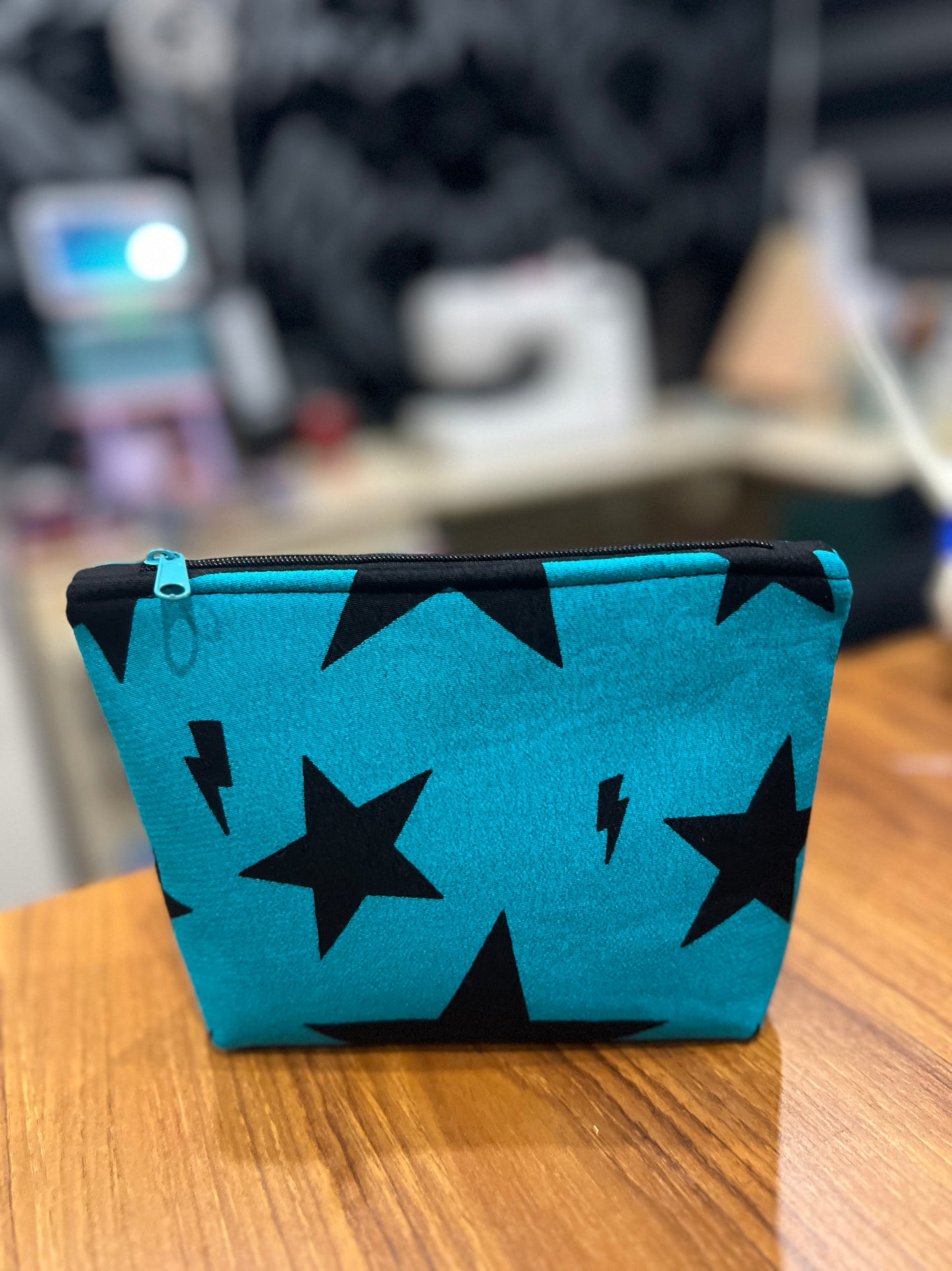 Teal pouch with black star patterns on a wooden surface