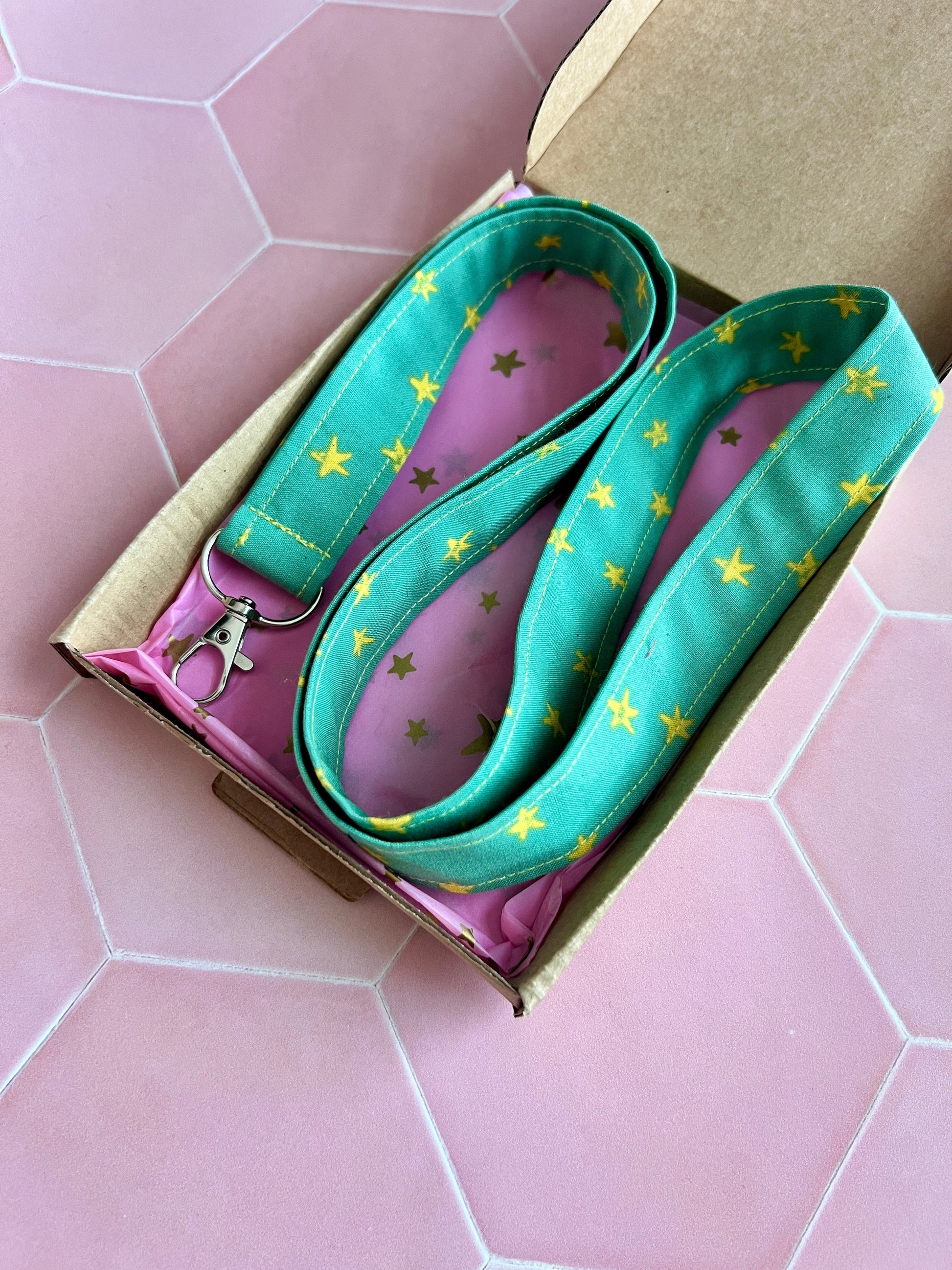 Sew Much Love green fabric lanyard with yellow stars and metal D-ring for keys and ID badges.
