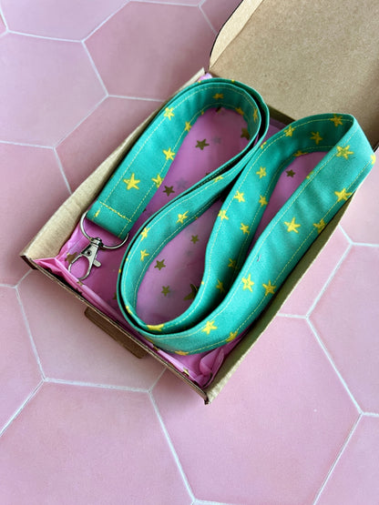 Sew Much Love green fabric lanyard with yellow stars and metal D-ring for keys and ID badges.