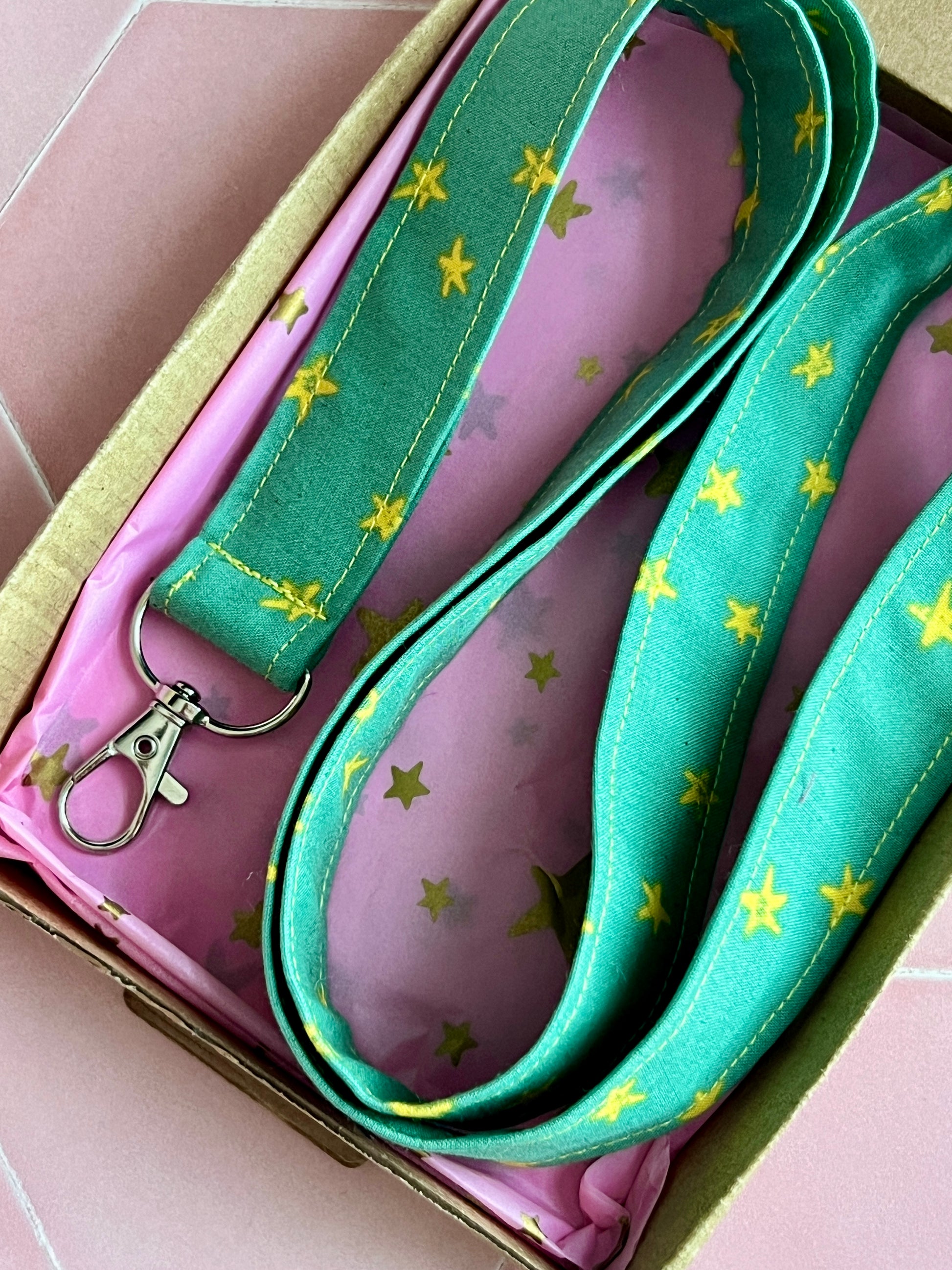 Close-up of handmade green star print lanyard for keys and badges, beautifully packaged in pink star tissue and kraft box