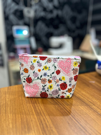 Sew Much Love mini cosmetic bag with white background, pink hearts, and colourful floral print. Features pink lining and a white zip.