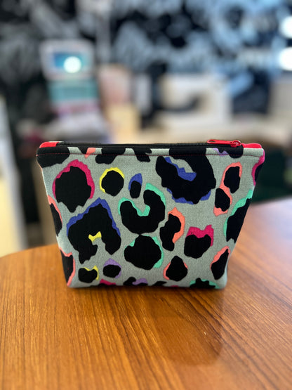 Sew Much Love mini cosmetic bag with grey background, black leopard print outlined in rainbow colours, and a red zipper.