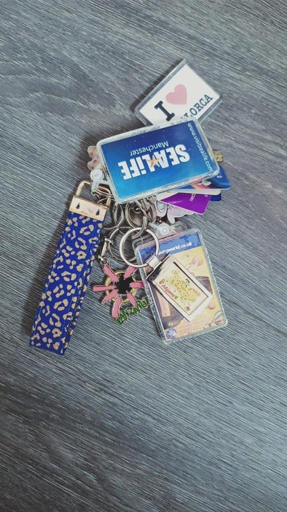Sew Much Love blue and gold leopard print cotton wristlet keychain with gold hardware and multiple souvenir keychains.