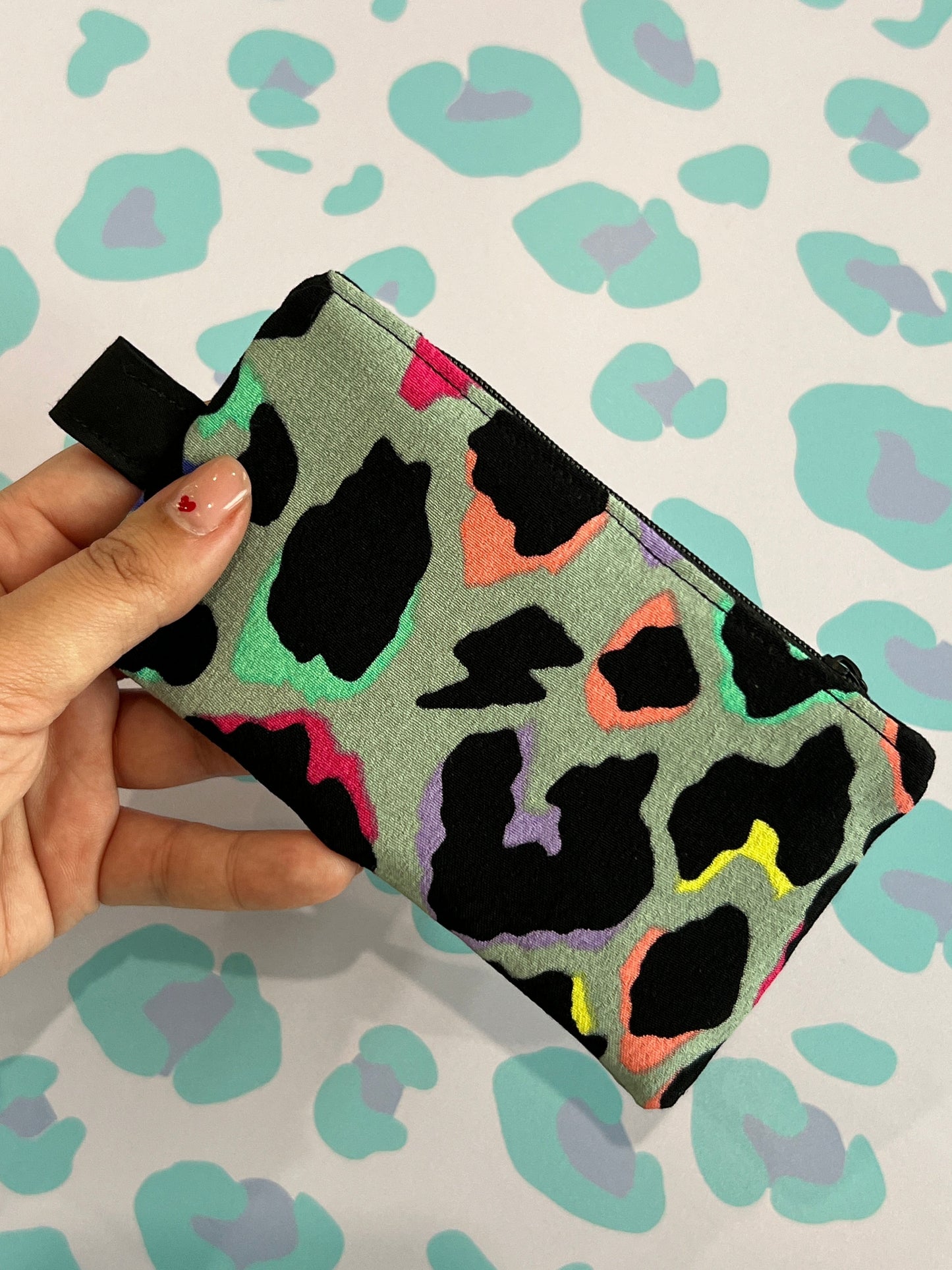 Sew Much Love limited edition coin purse with a grey base and a colourful leopard print in black, pink, green, yellow, and purple. Features a black zip and keyring attachment.