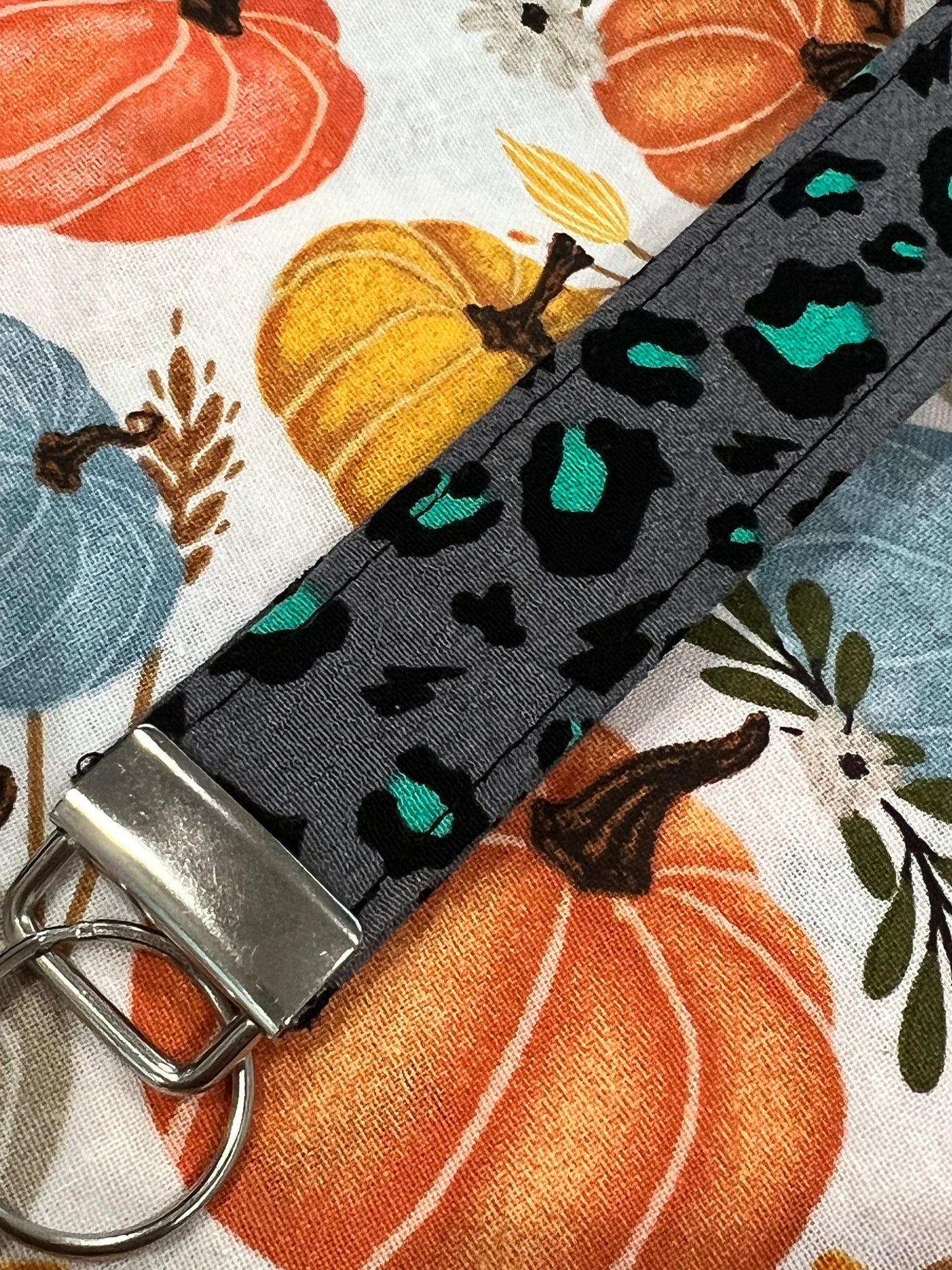 Sew Much Love grey wristlet keychain with black and teal snow leopard print, silver hardware.