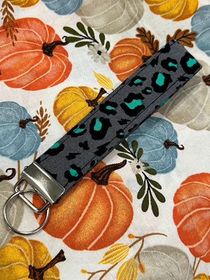 Sew Much Love grey wristlet keychain with black and teal snow leopard print, silver hardware.