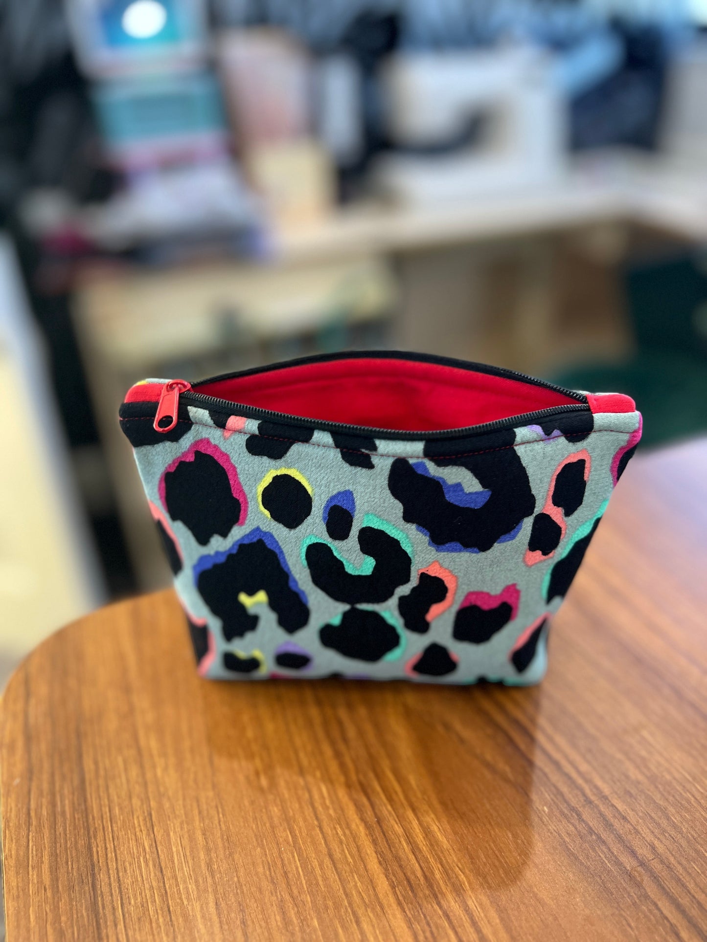 Sew Much Love khaki mini cosmetic bag with rainbow leopard print, black zip, and red lining.