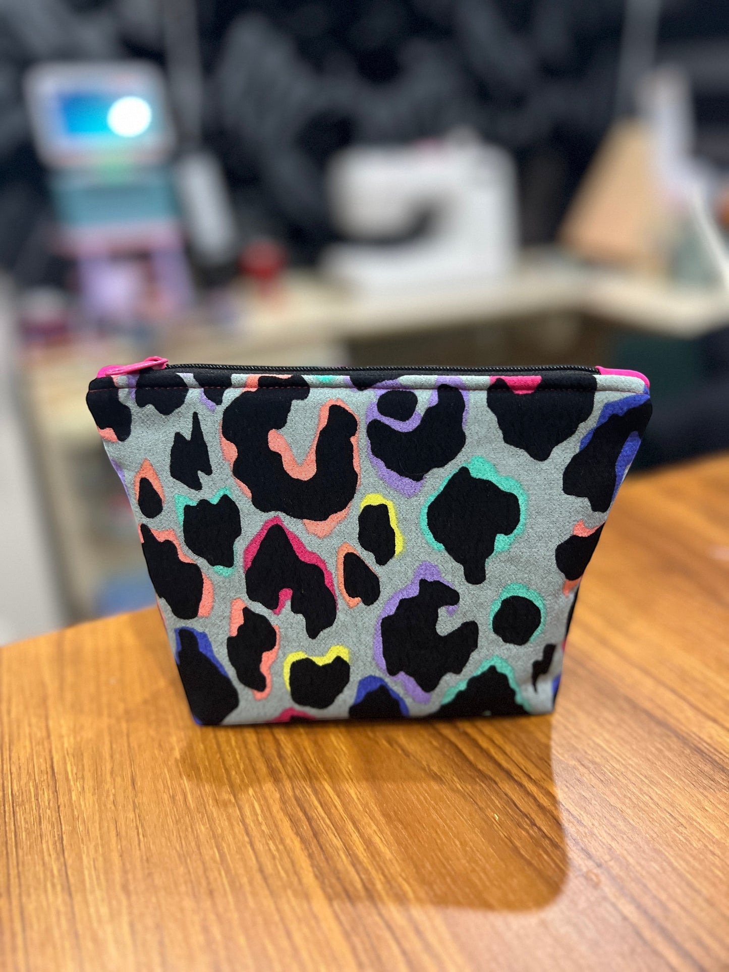 Sew Much Love mini cosmetic bag with grey background, black leopard print outlined in rainbow colours, and a pink zipper.