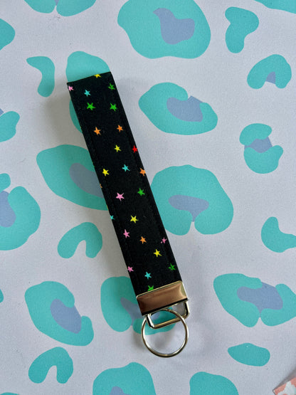 Sew Much Love black fabric wristlet keychain with small, colourful rainbow stars and silver hardware.