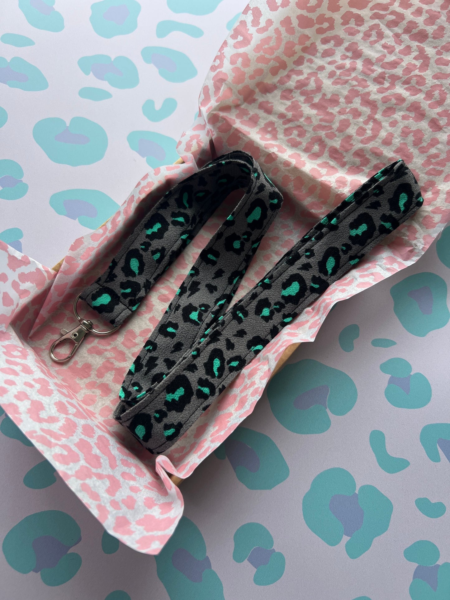 Sew Much Love handmade grey lanyard with a bold snow leopard print in black and teal, featuring a metal D-ring for keys and ID badges.