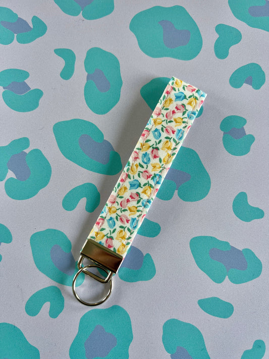 Sew Much Love wristlet keychain with a Tiny Tulips print in pink, yellow, and blue on white cotton with silver hardware.